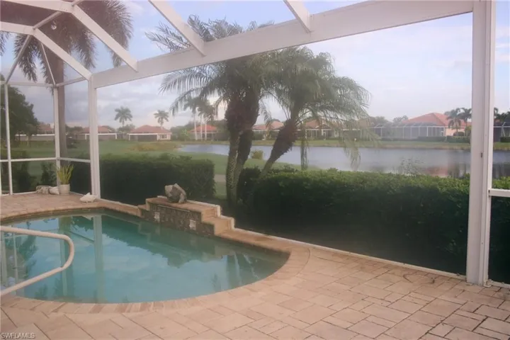 Outdoor pool featuring a patio area, a sunroom, glass enclosure, and a residential view