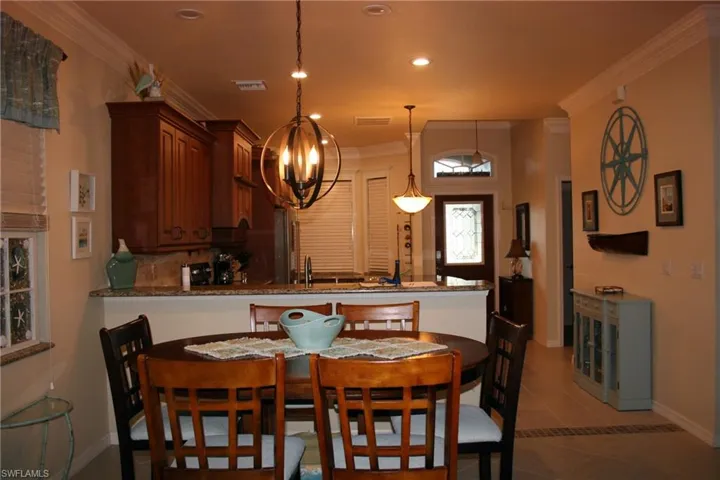 Dining space with ornamental molding, recessed lighting, and dark tile patterned floors