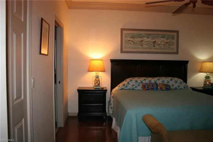 Bedroom with crown molding, dark wood-type flooring, and a ceiling fan
