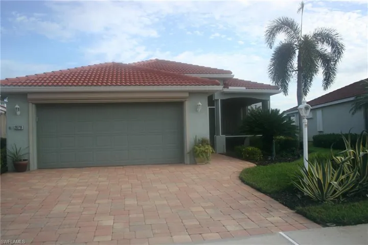 View of front of home with a garage, stucco siding, a tile roof, and driveway