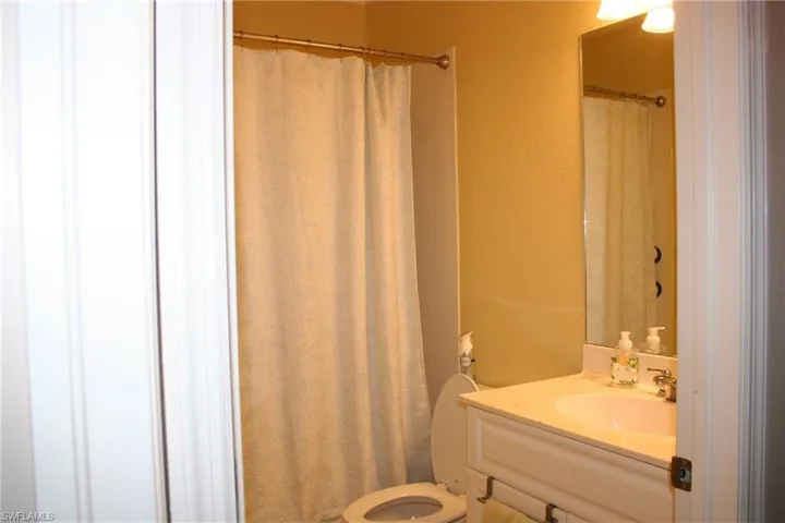 Full bathroom featuring a textured wall, a shower with curtain, and vanity
