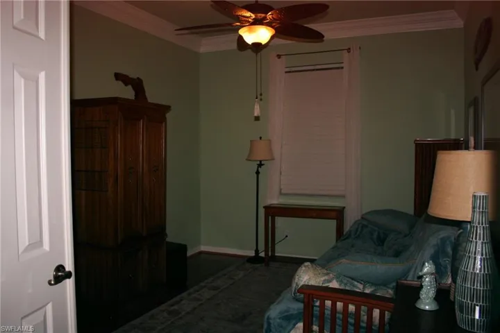 Bedroom featuring ornamental molding, a ceiling fan, and dark wood-type flooring