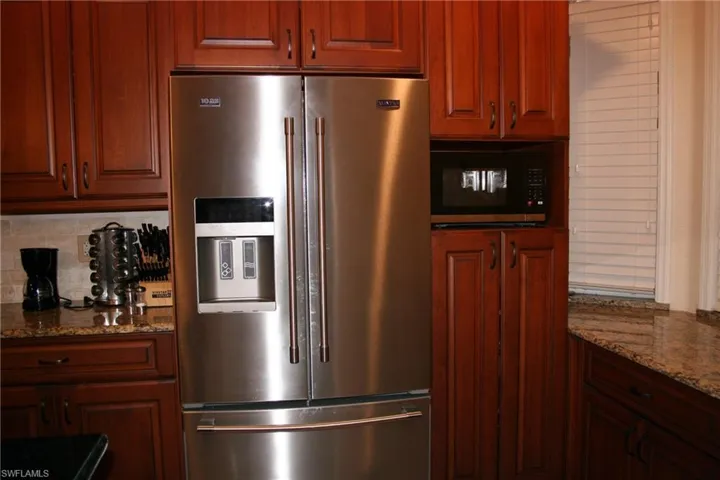 Kitchen with stainless steel appliances, dark stone counters, tasteful backsplash, and wood finish cabinetry