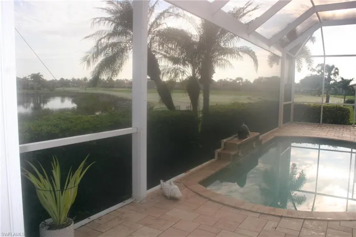 Outdoor pool featuring a sunroom, glass enclosure, and a water view