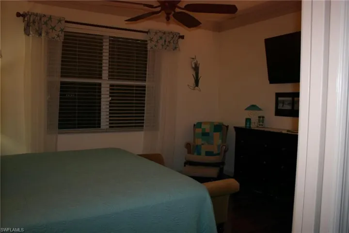 Bedroom featuring ornamental molding, ceiling fan, and dark wood finished floors