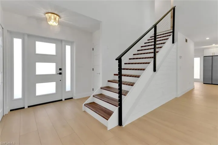 Entrance foyer featuring light hardwood & cable handrail.