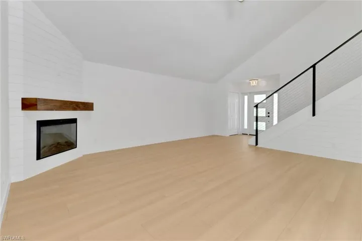 Unfurnished living room with high vaulted ceiling, light hardwood / wood-style floors, and a large fireplace