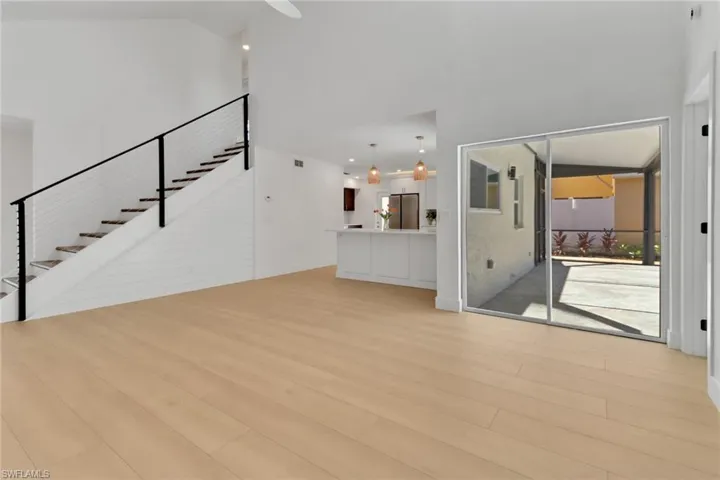 Unfurnished living room featuring a high ceiling and light hardwood / wood-style flooring