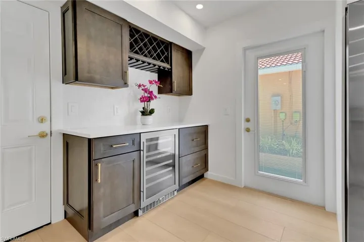 Bar with a wealth of natural light, wine cooler, accented custom cabinets.