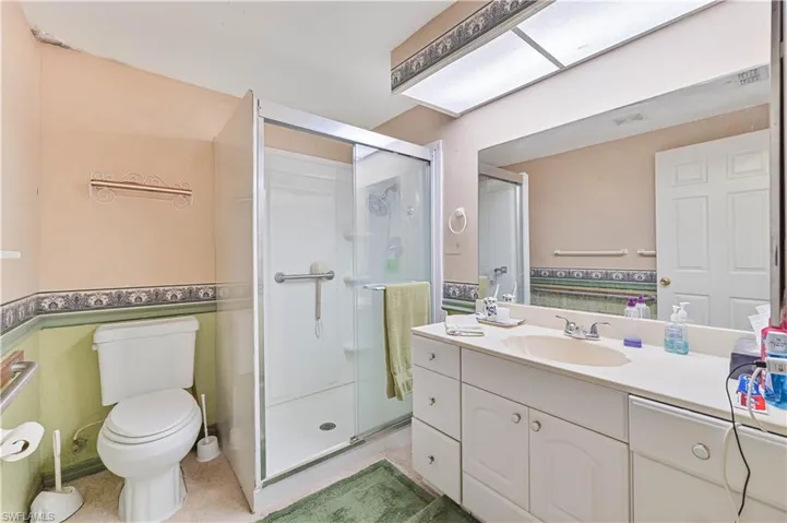Bathroom featuring walk in shower, vanity, and toilet