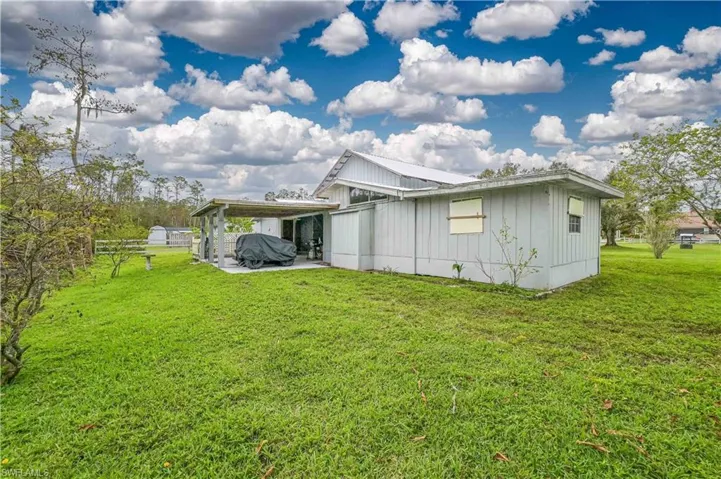 Rear view of property with a lawn and a carport