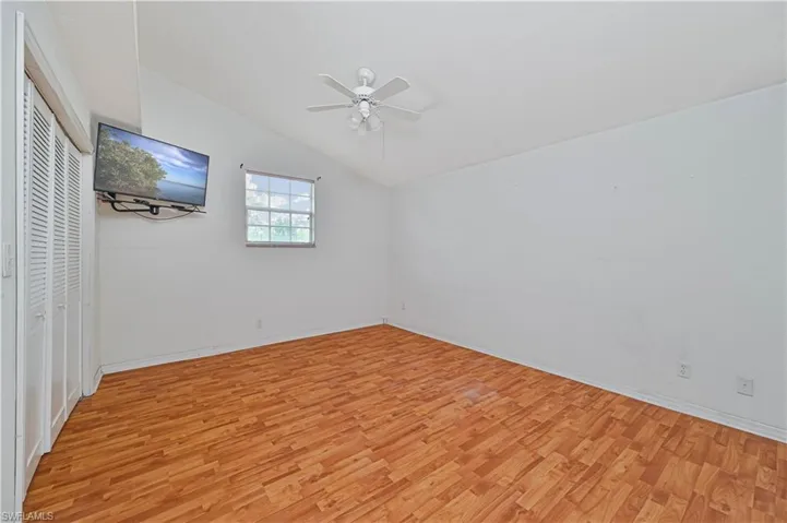 Unfurnished bedroom with ceiling fan, light wood-type flooring, and lofted ceiling