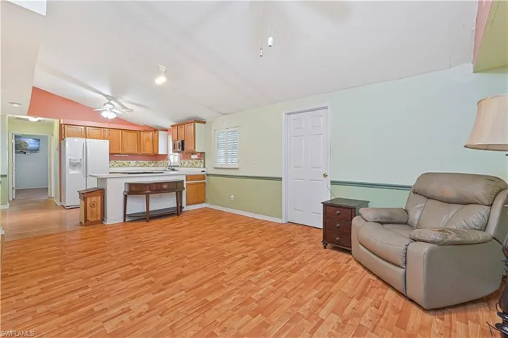 Living room with ceiling fan, sink, light hardwood / wood-style flooring, and lofted ceiling