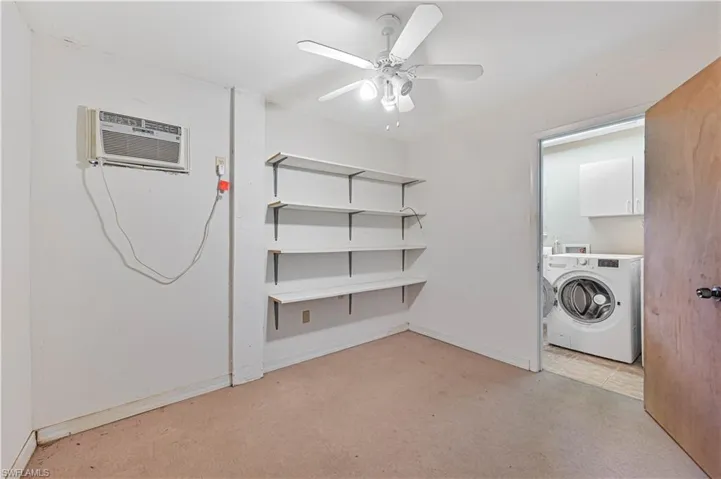 Washroom featuring cabinets, light carpet, ceiling fan, washer / dryer, and an AC wall unit