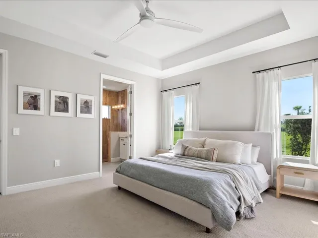 Bedroom featuring light carpet, a coffer ceiling, ceiling fan, and ensuite bath