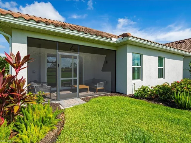 Rear view of house featuring a lanai, a tiled roof, stucco siding, and a lawn
