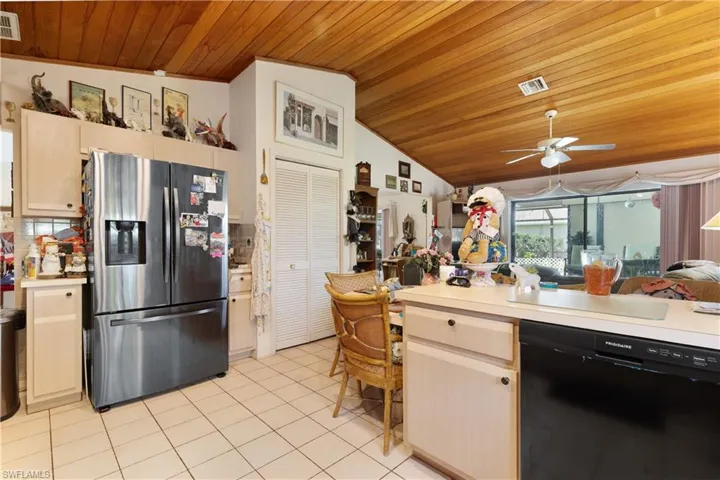 Kitchen featuring stainless steel fridge, black dishwasher, wood ceiling, open floor plan, and light tile patterned floors