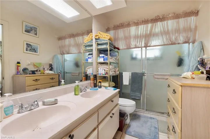 Bathroom with a stall shower, double vanity, and tile patterned flooring