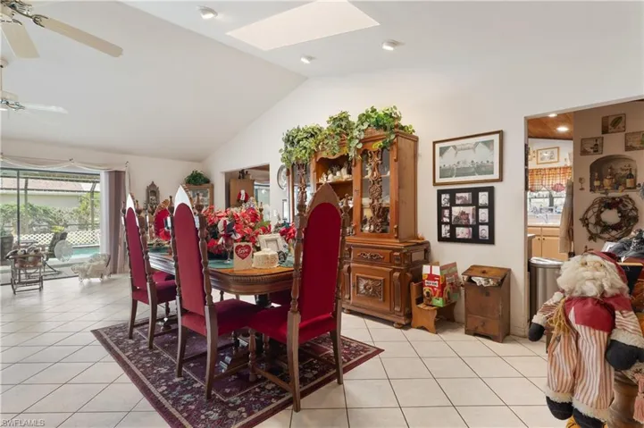 Dining area with a skylight, light tile patterned floors, a ceiling fan, and lofted ceiling