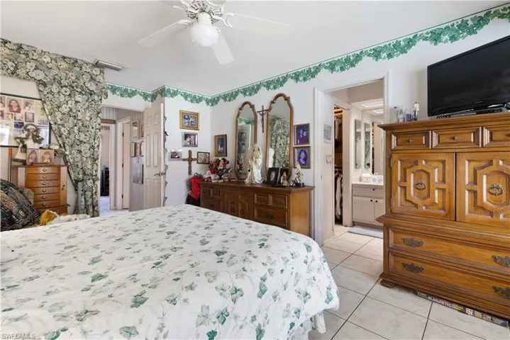 Bedroom featuring light tile patterned floors, ceiling fan, and ensuite bathroom
