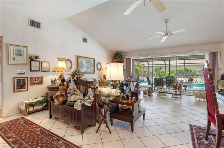 Living area with ceiling fan, light tile patterned flooring, and high vaulted ceiling