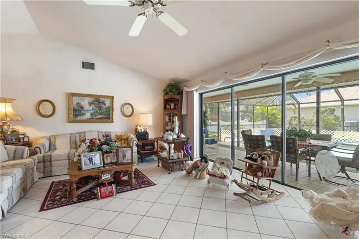 Living area featuring a ceiling fan, healthy amount of natural light, light tile patterned floors, and high vaulted ceiling