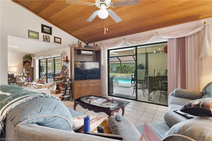 Tiled living area featuring wood ceiling, ceiling fan, and high vaulted ceiling
