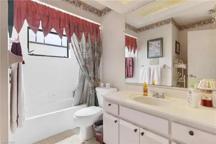 Full bath featuring vanity, shower / bath combo with shower curtain, and tile patterned floors