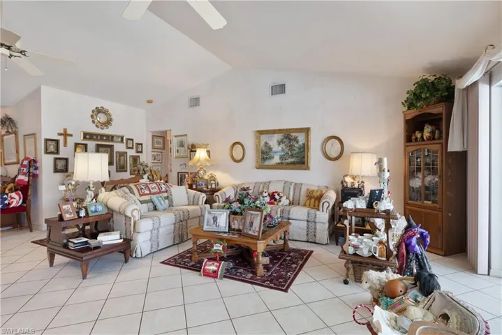 Living area with ceiling fan, light tile patterned floors, and high vaulted ceiling