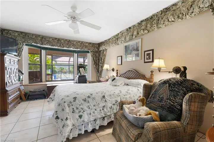 Bedroom featuring light tile patterned floors, bay window, and ceiling fan