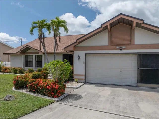 View of front of property with driveway, stucco siding, an attached garage, and a front lawn