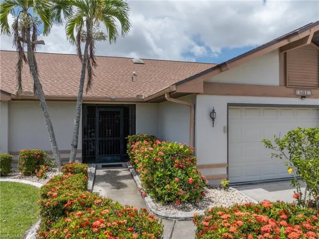 Entrance to property featuring roof with shingles, stucco siding, and an attached garage
