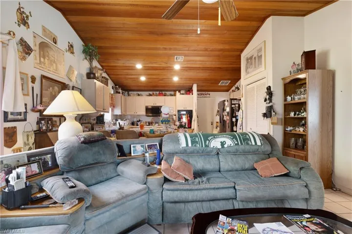 Living area featuring wood ceiling, light tile patterned flooring, a ceiling fan, and recessed lighting
