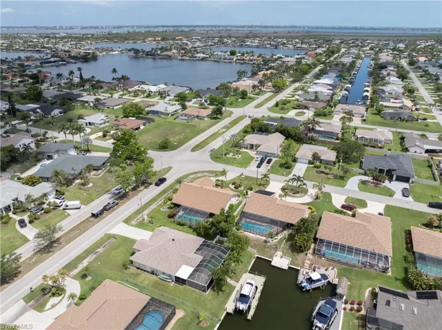 Aerial view of property and surrounding area featuring a nearby body of water and nearby suburban area