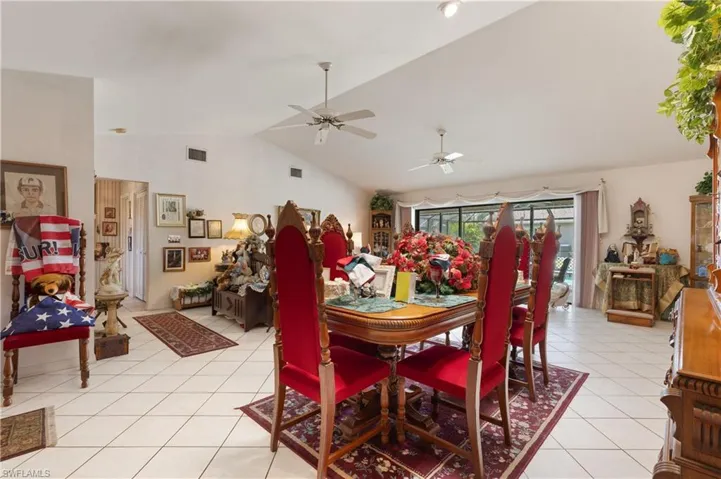 Dining room featuring vaulted ceiling, light tile patterned flooring, and a ceiling fan