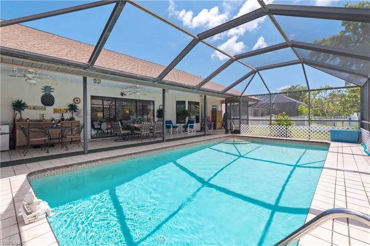 View of swimming pool with ceiling fan, a patio area, outdoor dining area, and a lanai