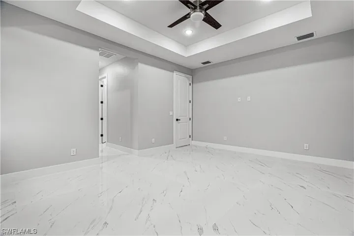 Unfurnished room featuring a tray ceiling and ceiling fan