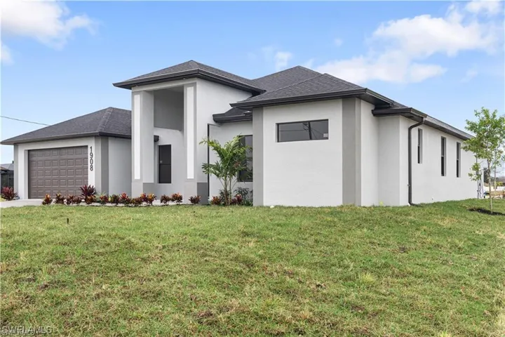 View of front facade featuring a front yard and a garage