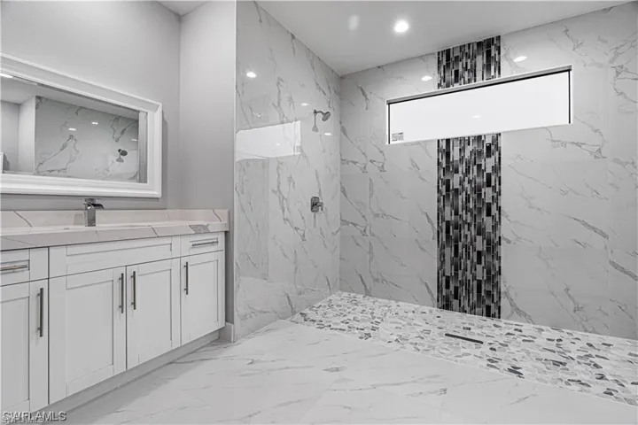 Bathroom with vanity and tiled shower