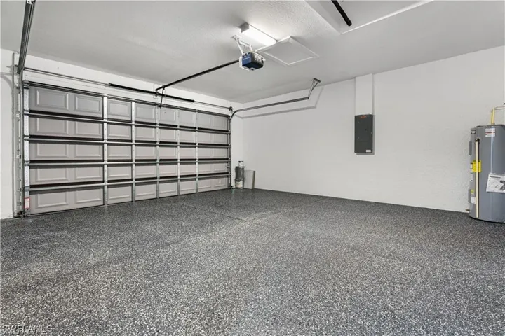 Garage with water heater, electric panel, and a garage door opener