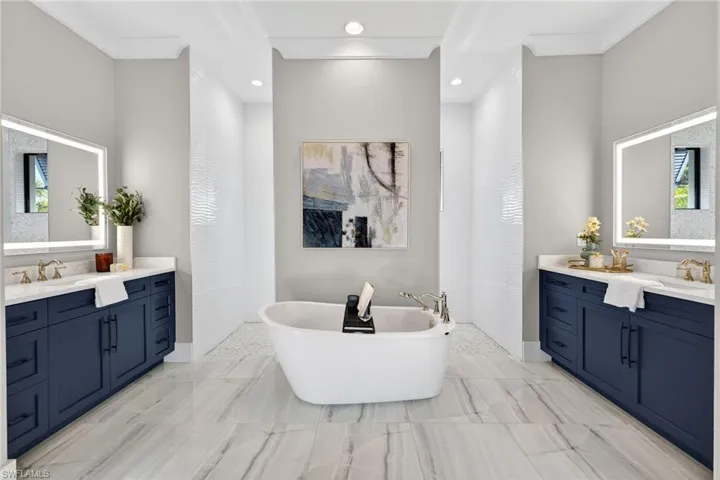 Bathroom featuring a freestanding tub, crown molding, two vanities, and recessed lighting
