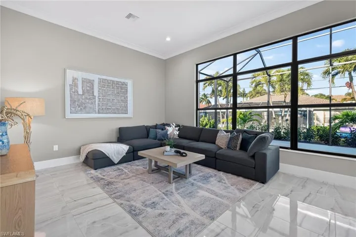 Living area with crown molding, light marble finish flooring, and recessed lighting