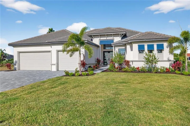 Prairie-style home with decorative driveway, a front yard, an attached garage, stucco siding, and a tile roof