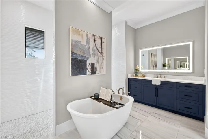 Full bathroom with vanity, a freestanding tub, ornamental molding, and walk in shower