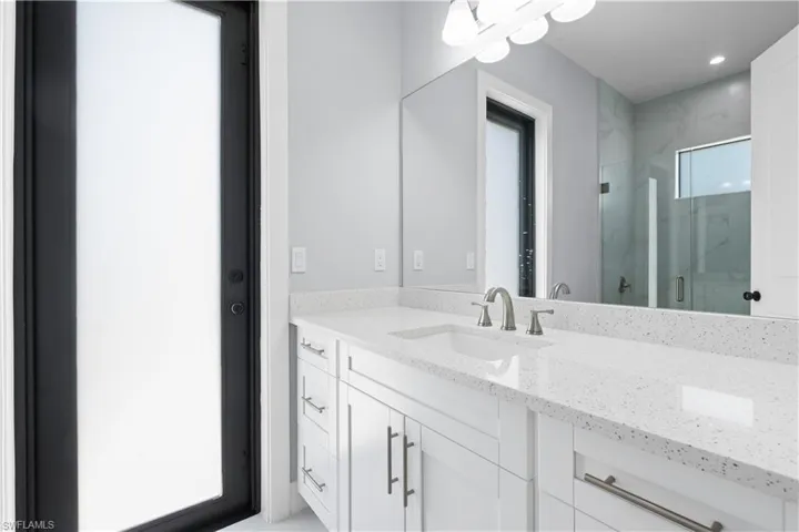 Contemporary bathroom vanity featuring white cabinetry, a light speckled countertop, and an integrated white sink
