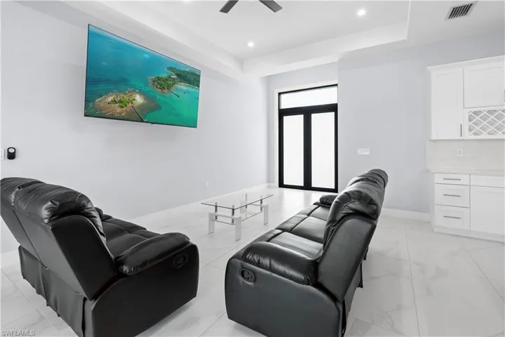 Spacious common area featuring light-toned tile flooring, a built-in wet bar with white cabinetry and a wine rack, and a ceiling fan