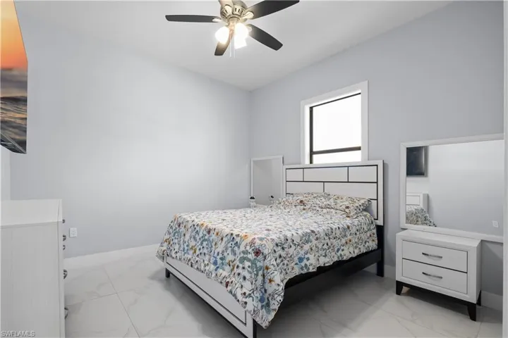 Spacious interior featuring light gray walls, large format tile flooring, and a ceiling fan with integrated lighting
