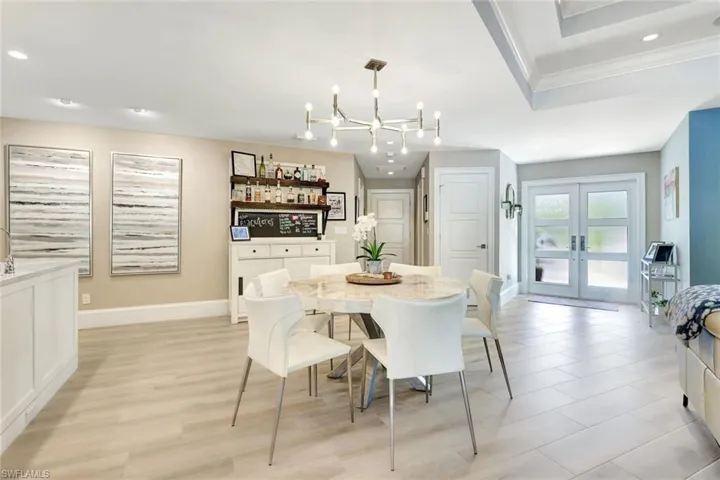 Dining space with french doors, light wood-type flooring, and an inviting chandelier