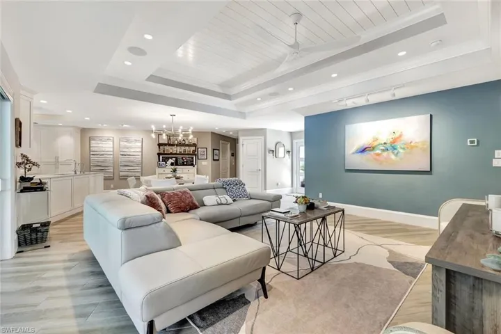 Living room featuring ornamental molding, a tray ceiling, and light wood-type flooring