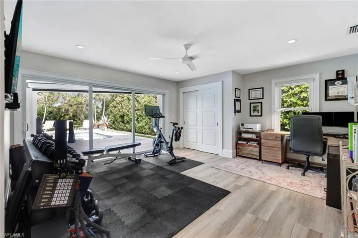 Exercise room with ceiling fan and light hardwood / wood-style flooring